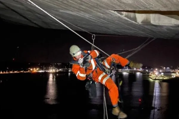A man abseiling off a bridge at night 